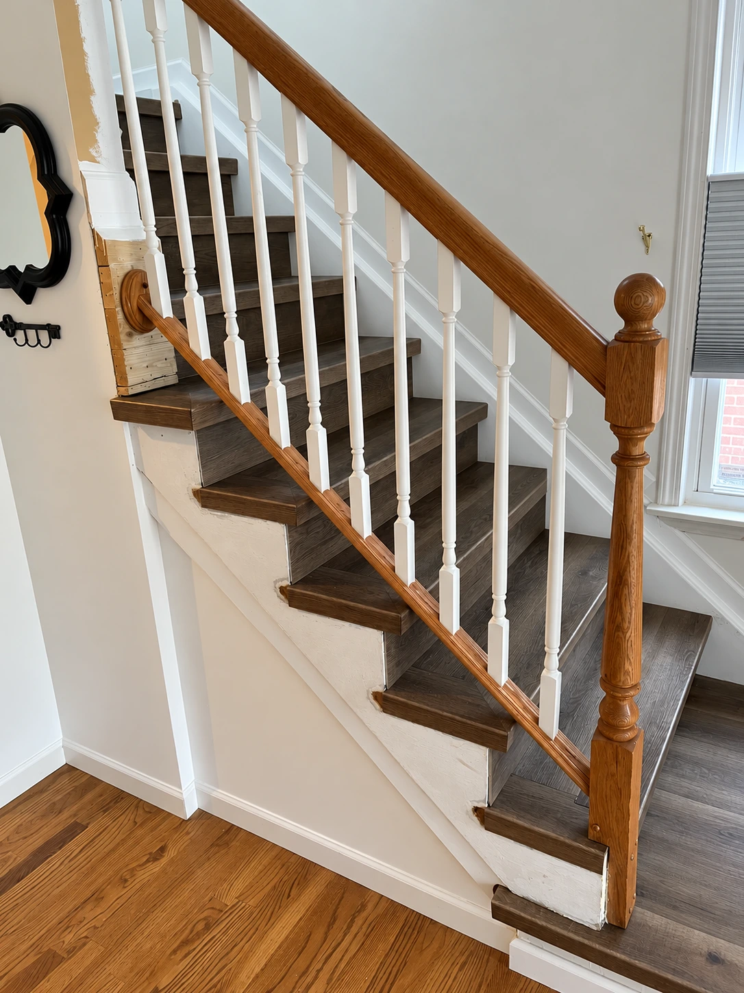 Side view of square-nose vinyl stair treads beside a wood handrail and white balusters